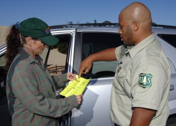 A forest service employee points to a brochure that a woman is holding