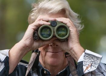A person holds up binoculars
