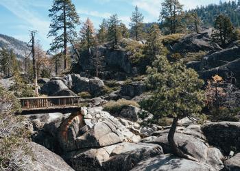 A wooden bridge spanning a granite outcropping with the Stanislaus River flowing beneath.