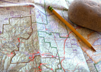 close up picture of a map with a pencil and rock on top of the map