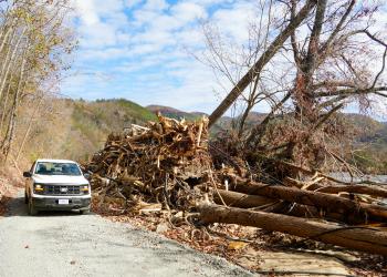 Forest Service pick up truck next to pile of trees and storm debris