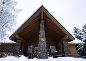 Front view of the Glacier Ranger District office building during the winter. Covered in snow.