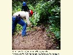 A trail worker digs trail tread with a pulaski.