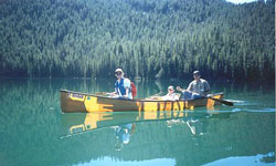Photo of two adults and a kid in a canoe on a lake.