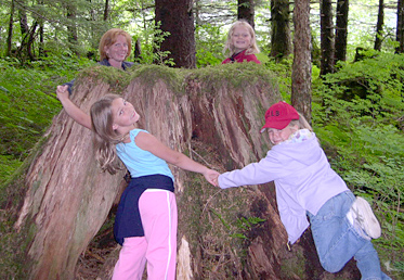 Kids hugging logged tree in Cordova, Alaska -- photo by USFS Kim Kiml