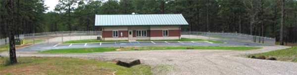 Photo of a building with a 10 stall parking lot and a fenced off area surrounding the perimeter.