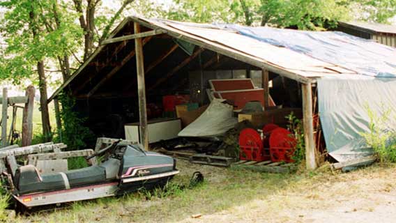 Photo of a run-down temporary shelter build of wood and tarp.