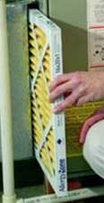 Photo of a person replacing a furnace filter.