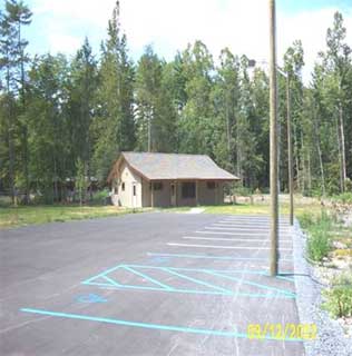 Photo of a parking lot with a building at the end of the lot.