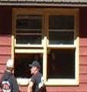 Photo of two people standing in front of two double hung windows.