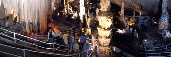 Photo of people standing on an elevator in a cavern.