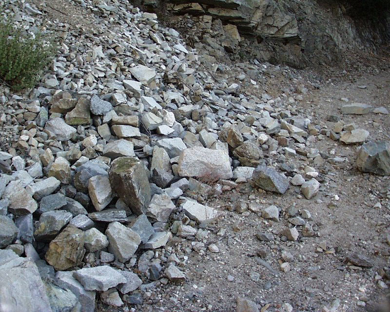 Material deposited on traveled way from a slide extending above the top of cut.