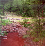 Deposition, clogging of lead out ditch with light cinder surfacing washed from traveled way.