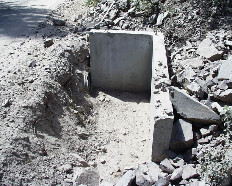 Ditch relief culvert inlet plugging prevented by concrete L shaped structure.
