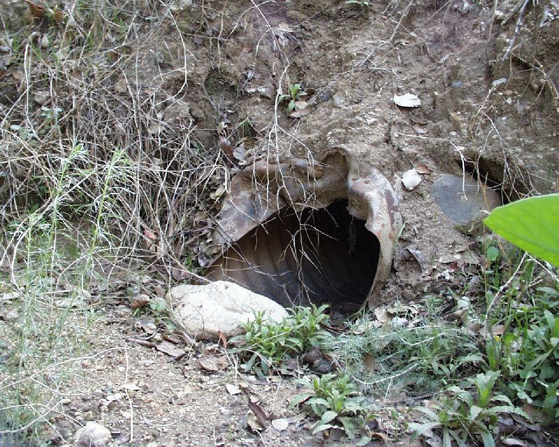 Inlet is partially plugged by rock and is dented by maintenance equipment.
