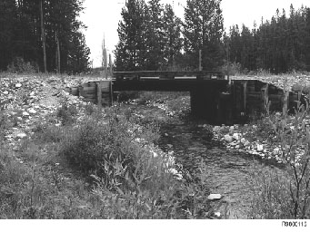 Figure 9LaMarche Creek Bridge, Beaverhead National Forest.  Typical single-span, treated timber bridge supported on vertical wall abutments, with wingwalls, on mudsills crossing a mountainous stream.