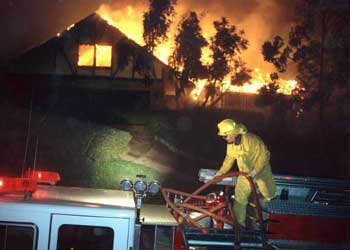 A photo of a firefighter removing a hose while fighting a wildland-urban intermix fire in San Diego County (Los Angeles Times Syndicate Photo, Don Barletti).