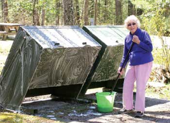 Photo of a campground host cleaning trash cans.