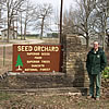 A Forest Service official standing next to the Seed Orchard sign, Superior Trees from Superior Seeds, Ouachita National Forest.