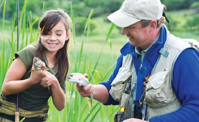 A man with a female child holding fish in their hands