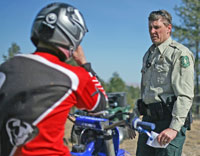 A US Forest Service law enforcement officer issues a citation to a dirt biker for operating a motor vehicle in a closed area.
