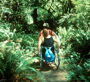 Photo of two people using wheelchairs on a trail.