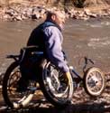 Photo of a man using a wheelchair with large front wheels and angled rear wheels.