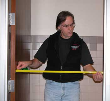 Photo of a man measuring the clear width of a doorway.