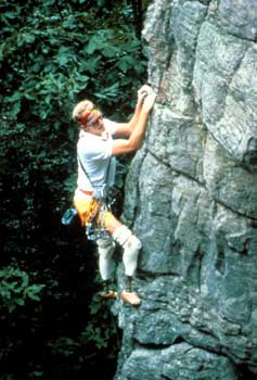 Photo of a man rock-climbing. The man is using two prosthetic legs.