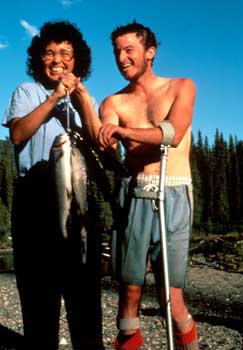 Photo of a woman and a man holding up a stringer of fish. The man is using metal balance supports that attach to his forearm near the elbow.
