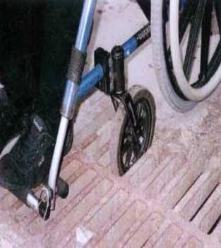 Photo of a wheelchair front wheel stuck in a grate.