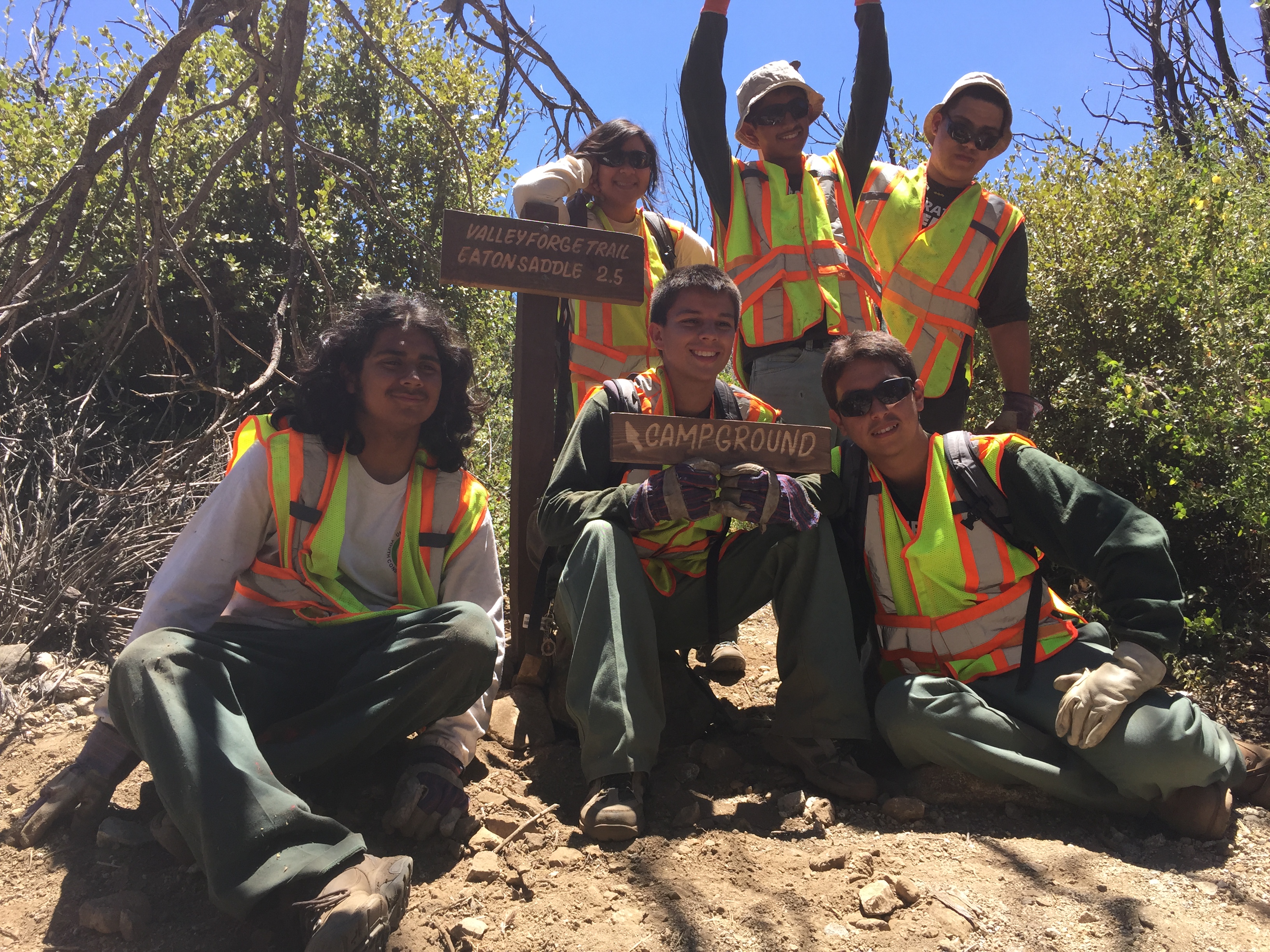 Image of young people posing near a trail sign.