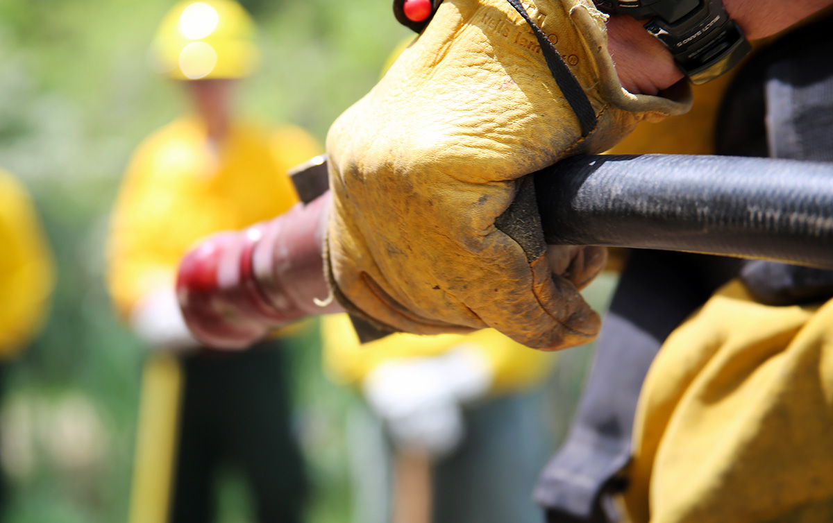 The gloved hand of a fire instructor grips a fire hose.