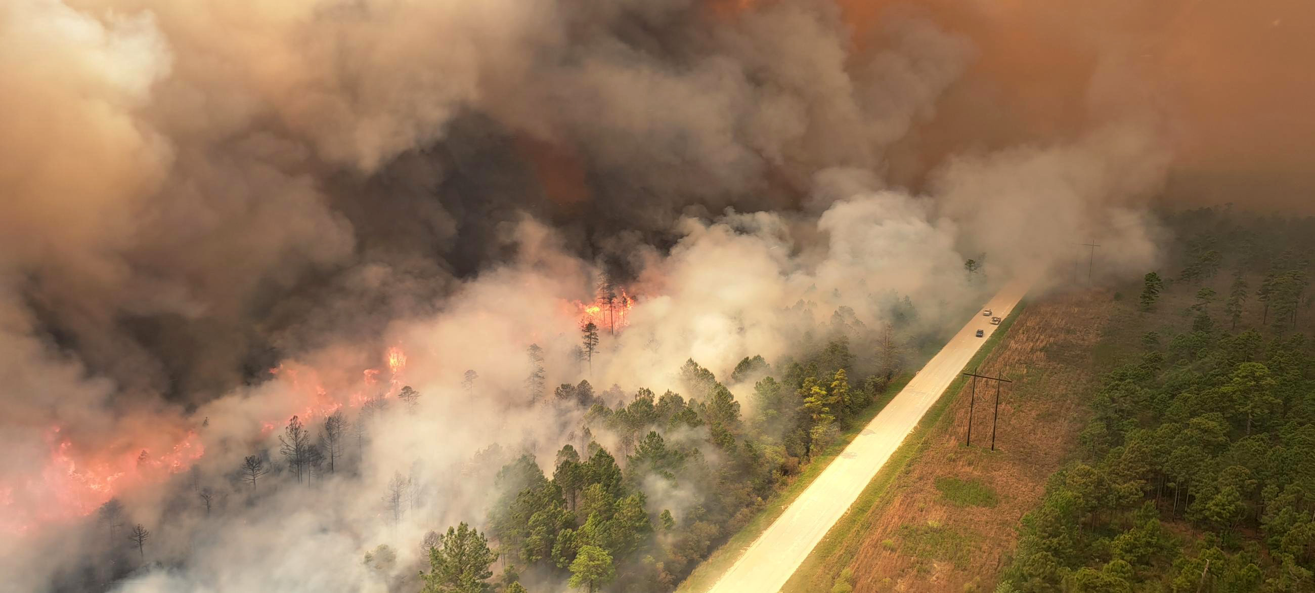 Aerial view of smoke billowing from fire near highway