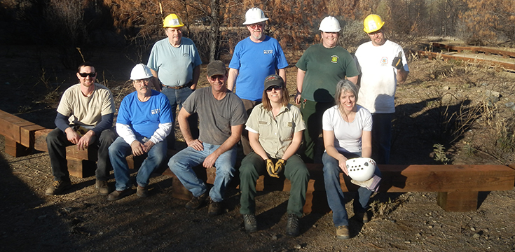 A picture showing nine trail volunteers; five sitting in the front and four standing in the back.