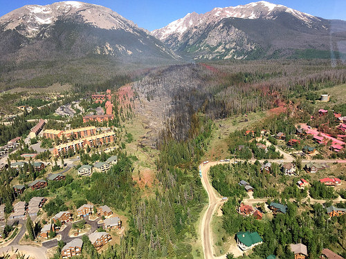 An aerial photo of a fuel break area in Colorado, with homes and other structures seen on either side.  The Rocky Mountains can be seen in the background.