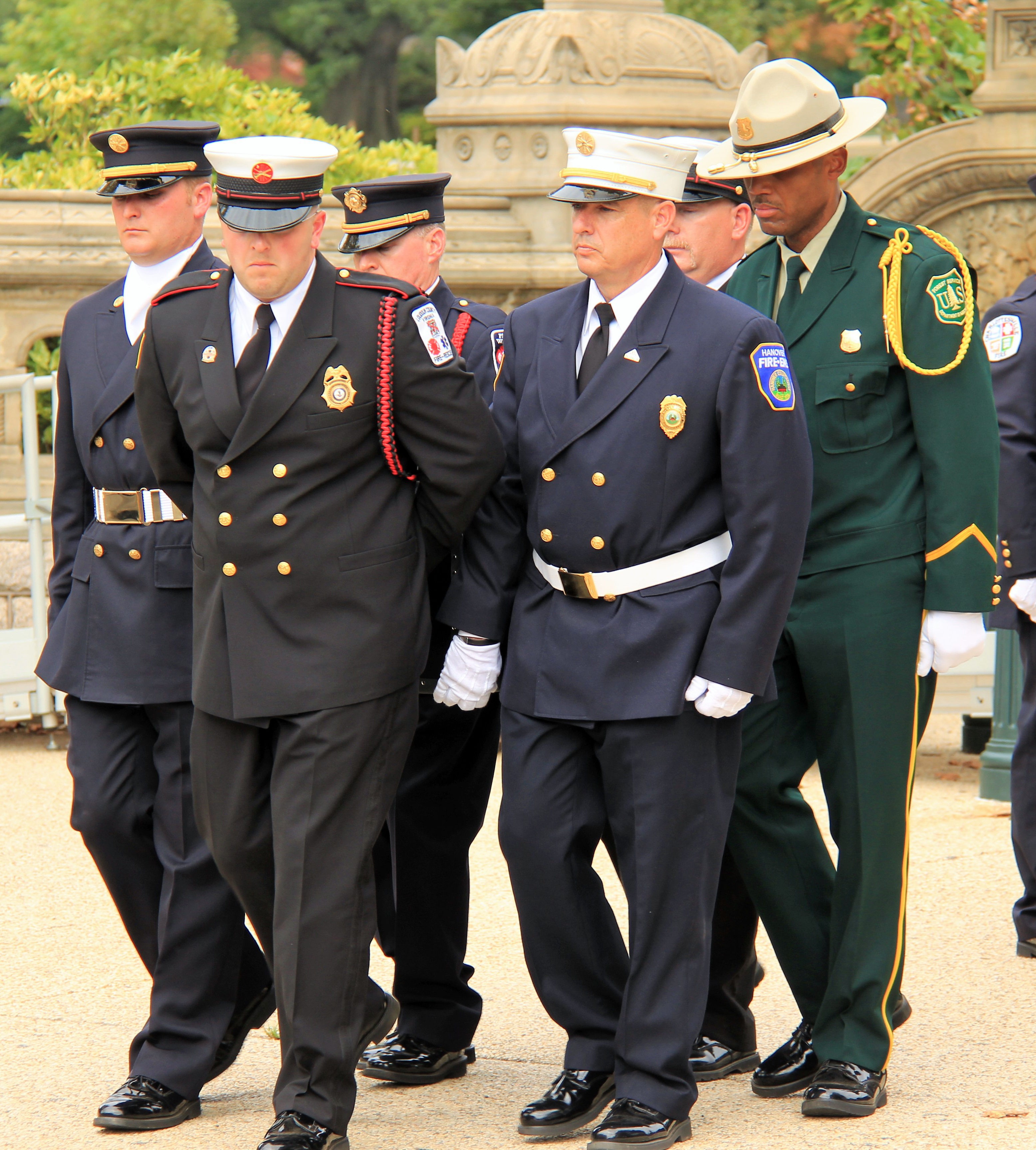 Men in uniforms of various agencies standing outside at the National Fallen Firefighter Foundation Memorial.