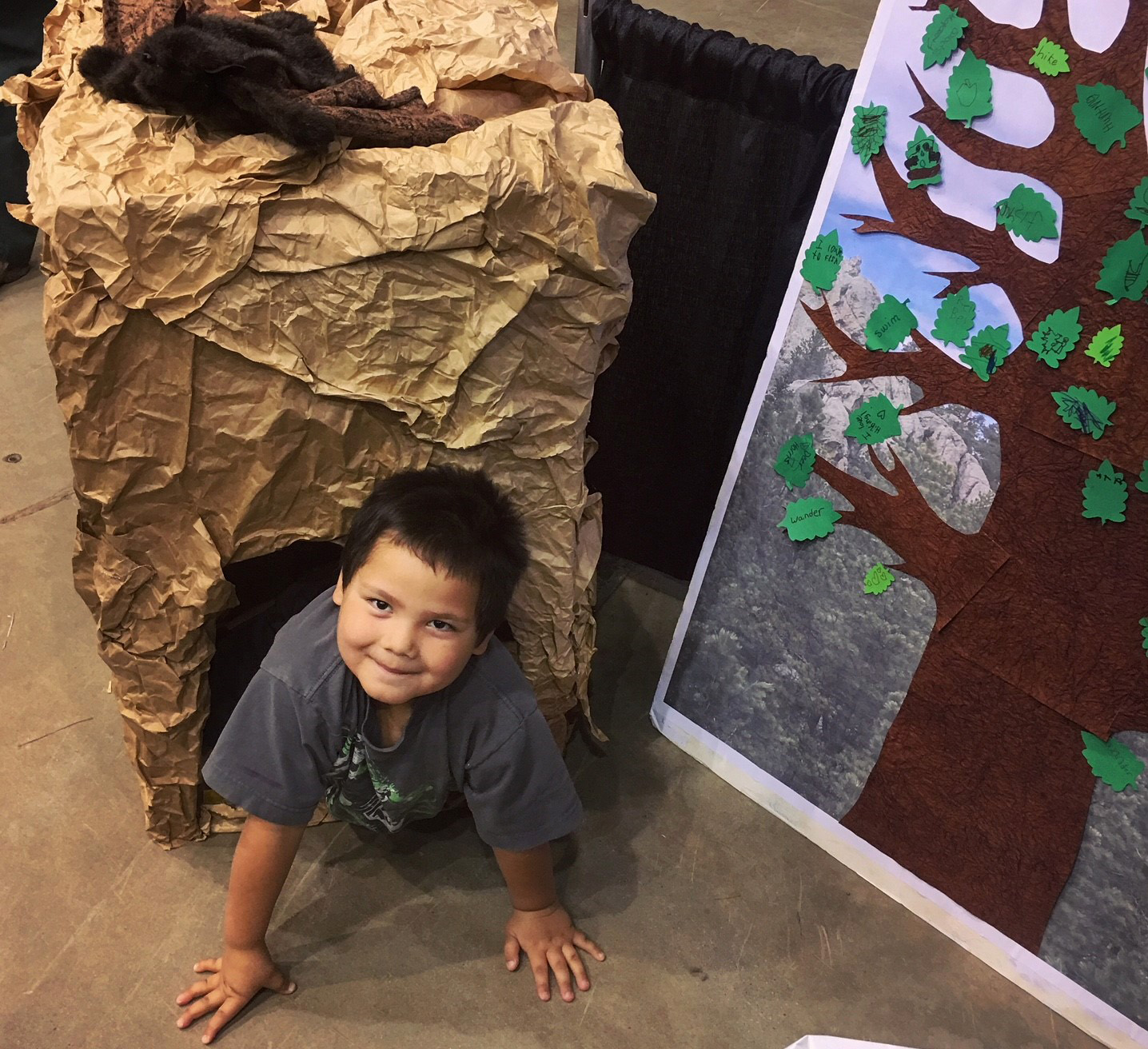 Photo: A child looks up from the floor as he craws out of a paper cave.