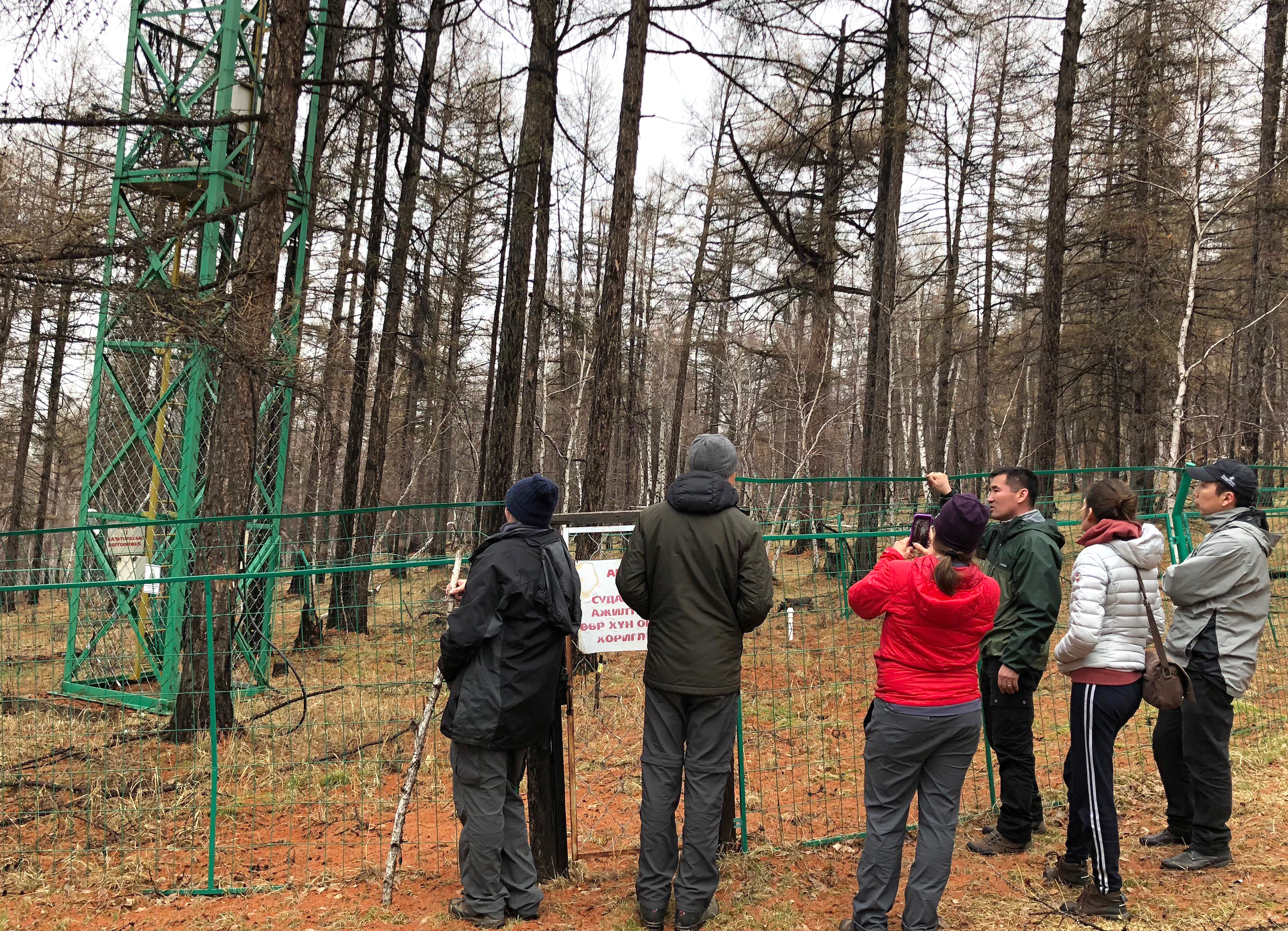 Photo: Group stands outside fence at automated weather station.