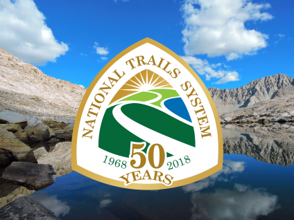 A picture with the National Trails System 50 years (1968 to 2018) logo and with high elevation lake and mountains in the background