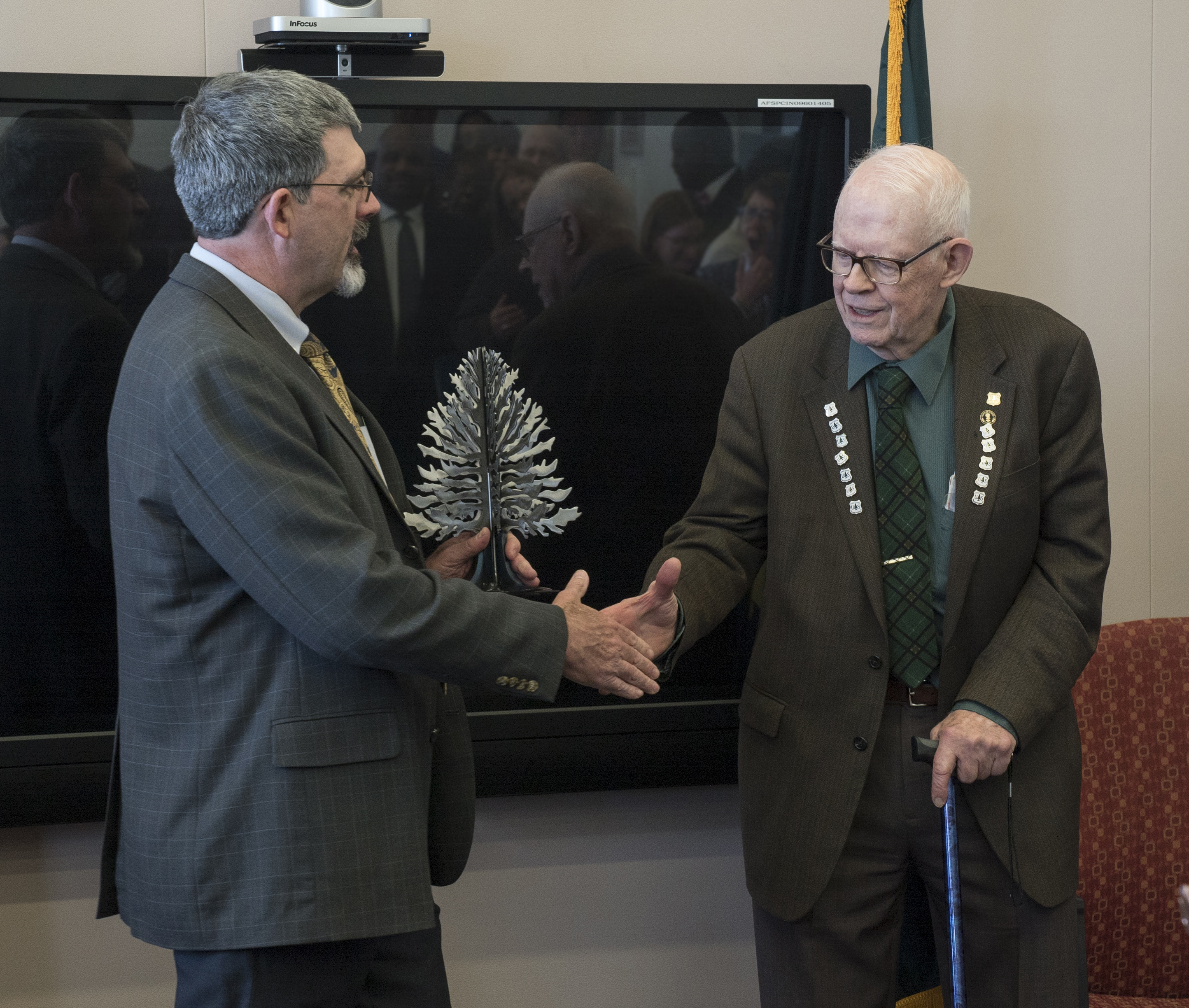 Photo: Rowley presents award to Fitzgerald. Award is in the shape of a tree and made of metal.