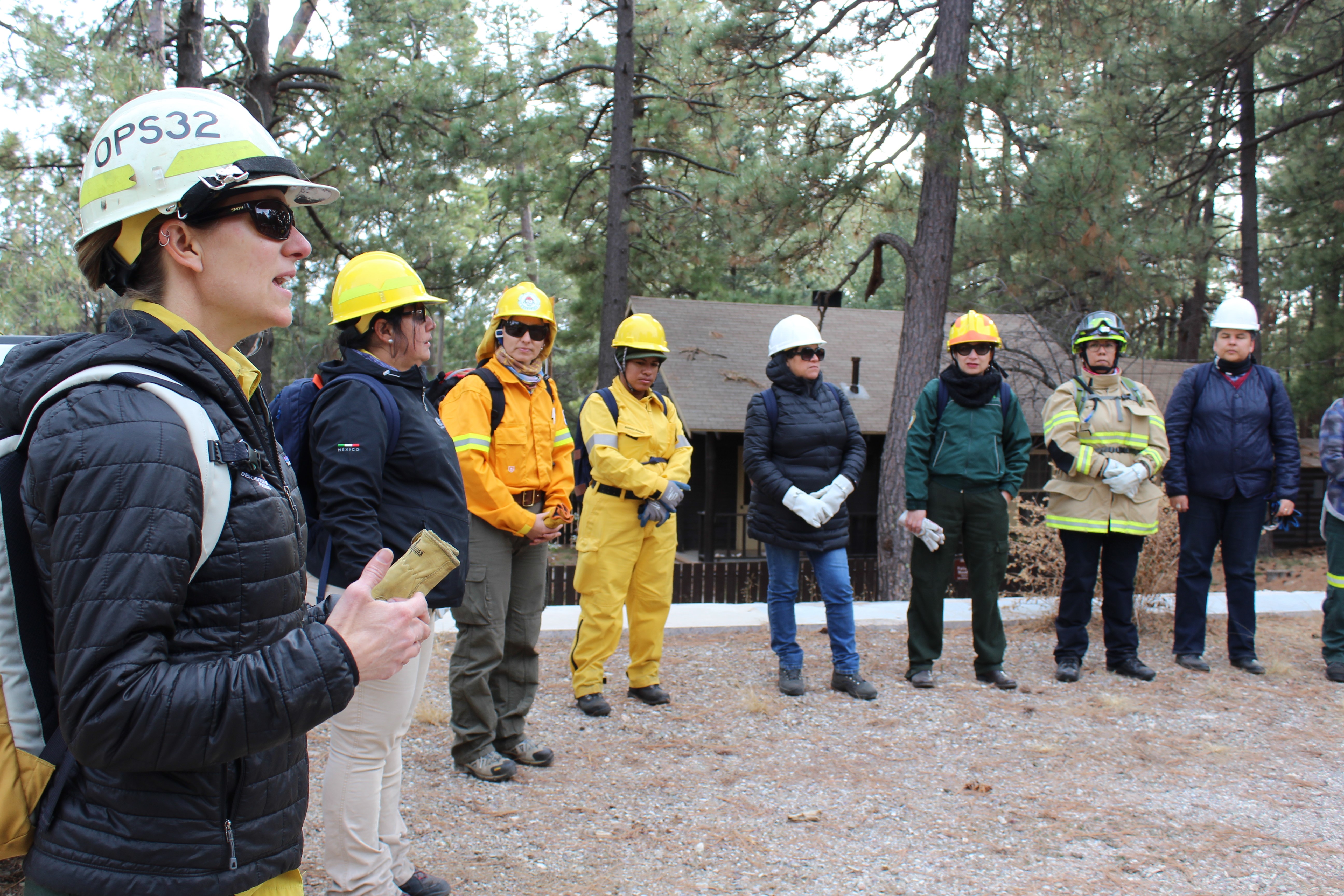 Photo: Women in safety gear stand in circle as one member of the group speaks.