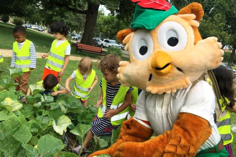 A picture of Woodsy Owl working with several young kids.