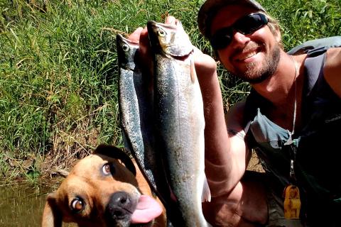 The author and his best friend and teammate, Badger, pose for a photo with two sea-run cutthroat trout while on a fishing the tidewaters of a Siuslaw National Forest river last July.