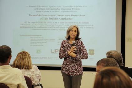 Woman standing in front of a room addressing the gathered group