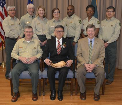 A picture of Ge Sun receiving a Chief's Award, photographed with all the members of the Forest Service executive leadership team in uniform.