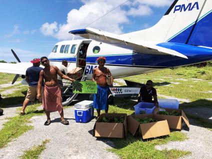 Five men offloading boxes of food supplies from a small private plane