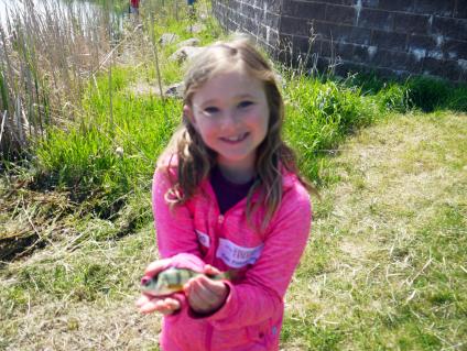 Kid holding fish on the palm of her hands