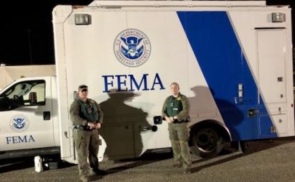 Two women in uniform, standing in front of FEMA truck