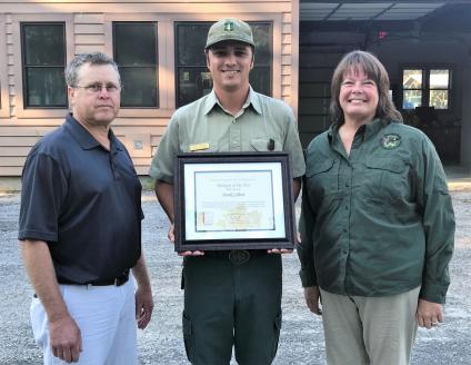 Derek Colbert poses with his biologist of the year award and Ray Metzler and Ericha Nix.